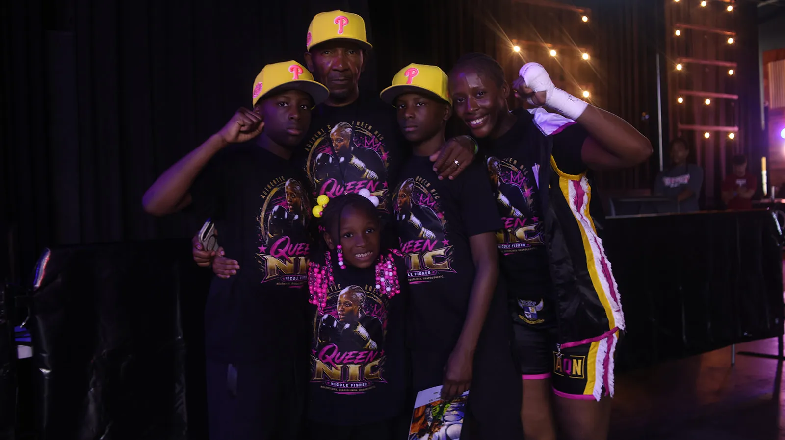 Fisher in her ring gear with her three children and a family member, all in Queen Nic shirts.