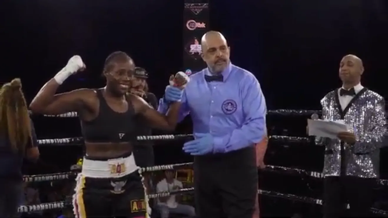 Nicole Fisher raises a fist as the referee holds her other hand aloft after the decision is announced.