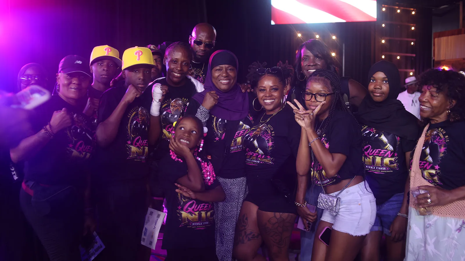 A large group of supporters in Queen Nic shirts posing together at the arena.