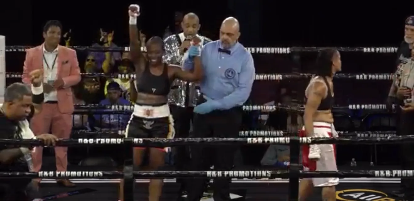 The referee raises Fisher's hand as the ring announcer reads the scorecards; Cotton stands in the far corner.